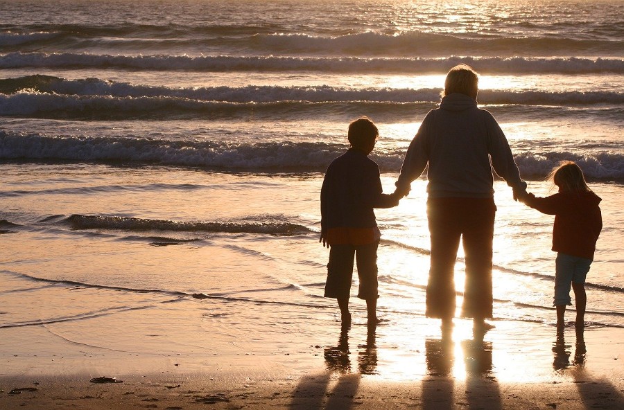 mother holding hands of two children at beach