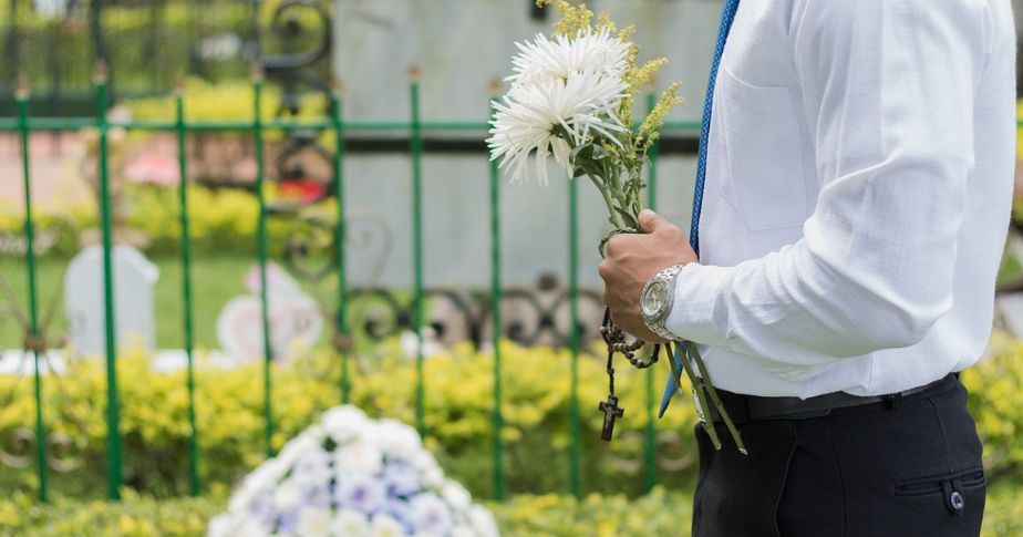 man holding flowers at cemetery