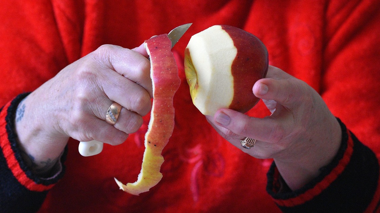 two hands peeling an apple