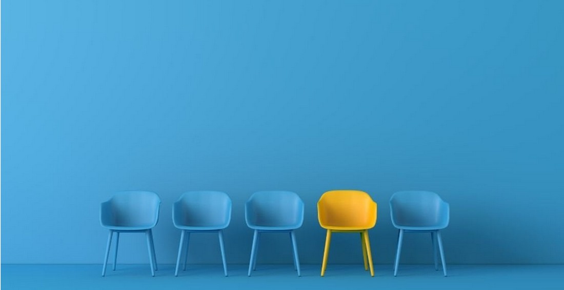five empty chairs, one yellow, the rest blue