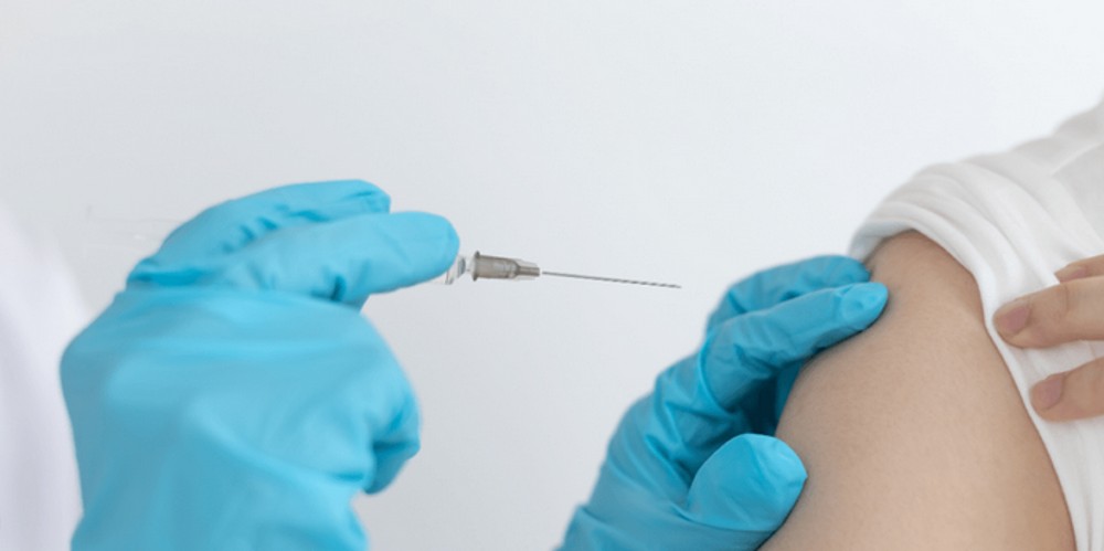 hands administering injection to arm