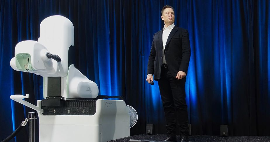 Elon Musk standing next to an invention